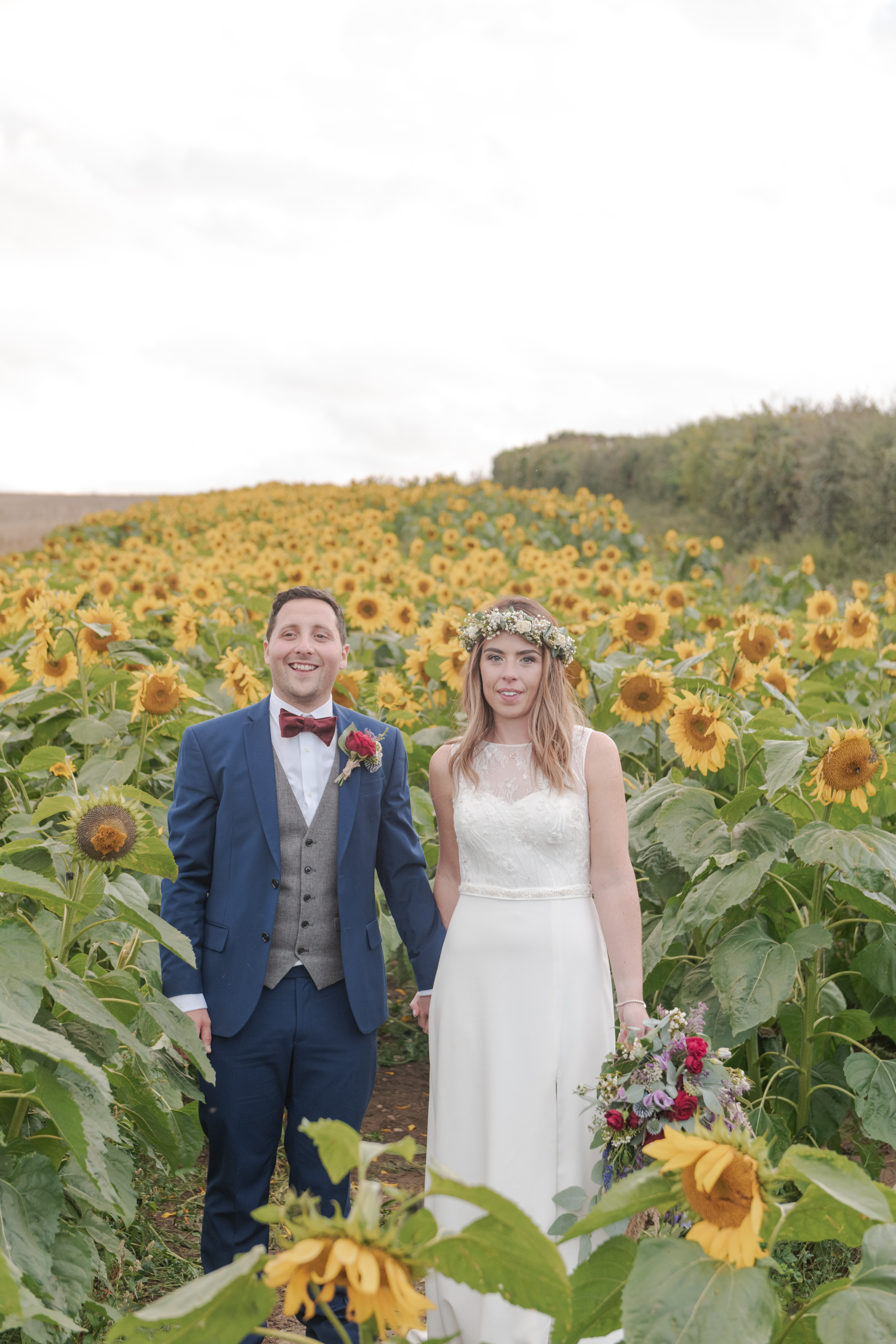 Smiling Couple on there wedding day photographed in a sunflower field at Rosedew Farm